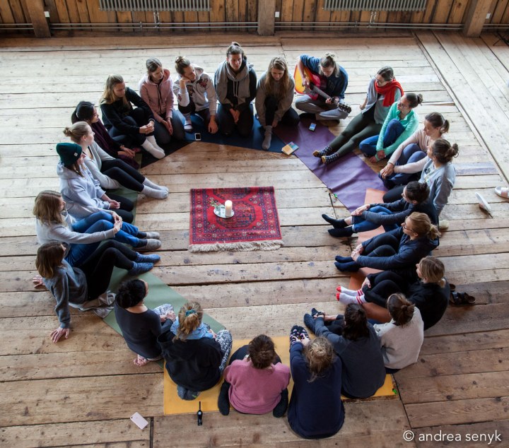 Yogis sitzen im Kreis um eine Kerze in Hütte